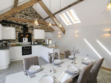 A kitchen and dining area with stone wall and wooden beams at Rhyd Angharad Barns in Rhydwyn