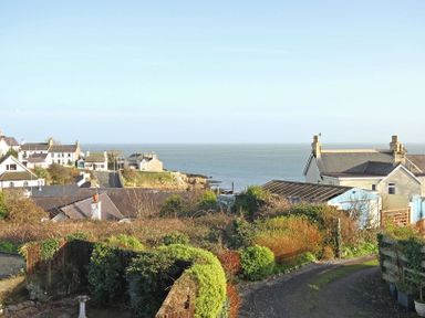 A coastal village with houses and a road leading to the sea at Seiriol View in Moelfre
