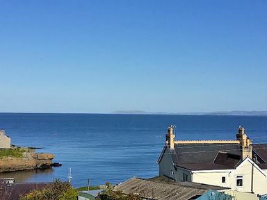 A coastal view with a house and a rocky shoreline overlooking the sea at Seiriol View in Moelfre