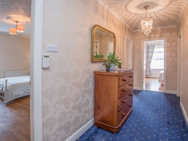 A hallway with a wooden chest of drawers and a mirror above at The Mermaid in Brynsiencyn