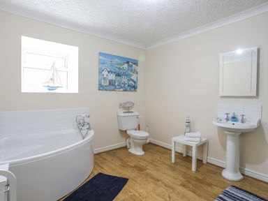 A bathroom with a bathtub toilet sink mirror and table with towels at The Mermaid in Brynsiencyn