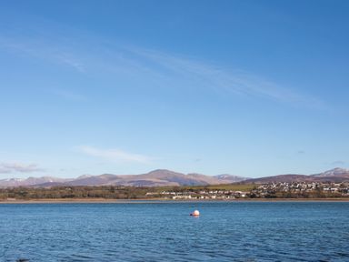 A body of water with houses and hills in the background at The Mermaid in Brynsiencyn