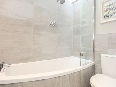 A bathroom with a bathtub shower combination and a toilet at The Honey Pot in Garndolbenmaen