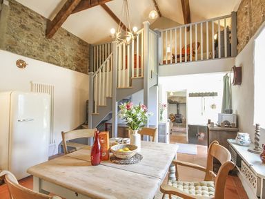 A kitchen dining area with wooden table chairs flowers and a bowl of fruit under exposed beams at Three Gates in Llangoed