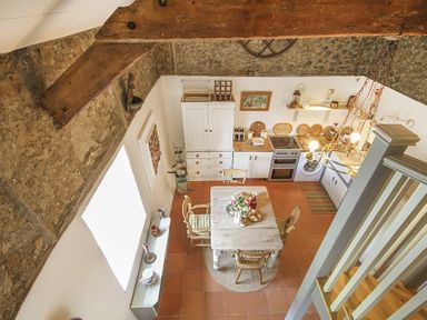 A kitchen and dining area with wooden beams terracotta floor and a table with chairs at Three Gates in Llangoed