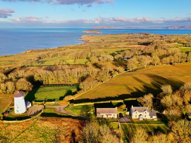 A rural landscape with a white windmill and houses near the coastline at Three Gates in Llangoed