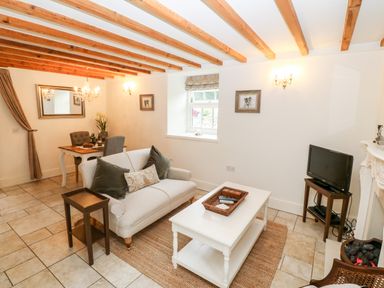 A living room with a sofa coffee table television and dining table at The Little Coach House in Garndolbenmaen