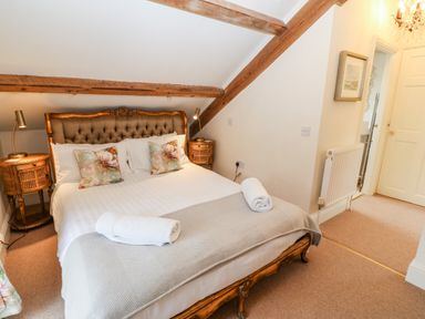 A bedroom with a double bed and wooden beams with bedside tables and lamps at The Little Coach House in Garndolbenmaen