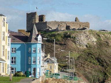A street with houses and a stone castle on a hill at The Towers - Castell in Criccieth
