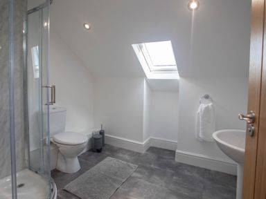 A bathroom with a toilet shower sink towel and skylight at The Towers - Castell in Criccieth