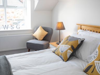 A bedroom with a bed pillow chair and lamp next to a window at The Towers - Castell in Criccieth