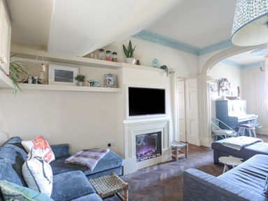 A living room with blue sofas a fireplace and a television above it at Towyn Lodge in Trearddur Bay