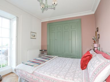 A bedroom with a bed red pillows and a green built in closet at Towyn Lodge in Trearddur Bay