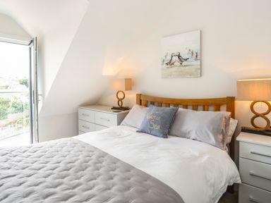A bedroom with a wooden bed frame and bedside tables with lamps at The Pot Loft in Benllech