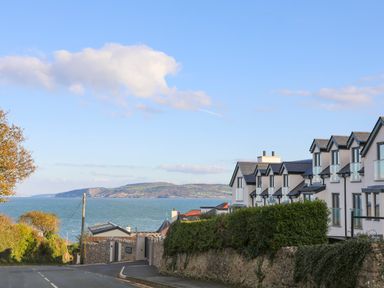 A street with houses and a view of the sea and hills at The Pot Loft in Benllech