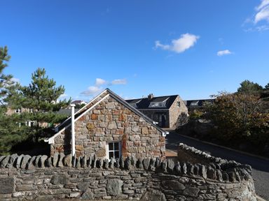 Stone cottages with slate roofs behind a stone wall on a clear day at Tyn Towyn - Bwthyn Haf in Trearddur Bay