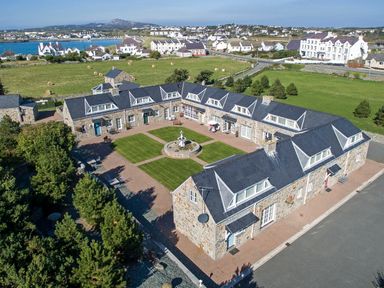 A courtyard with a fountain surrounded by stone buildings in a rural area at Tyn Towyn - Bwthyn Haf in Trearddur Bay