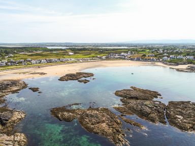 A coastal area with a sandy beach rocks and houses near the shore at Tyn Towyn - Ty Glas in Trearddur Bay