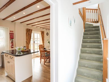A kitchen island with countertop and a carpeted staircase with wooden railings at Tyn Towyn - Ty Oren in Trearddur Bay