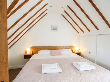A bedroom with a double bed two bedside lamps and folded towels on the bed at Tyn Towyn - Ty Oren in Trearddur Bay