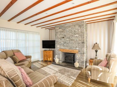 A living room with sofas a stone fireplace and a television at Tyn Towyn - Ty Piws in Trearddur Bay