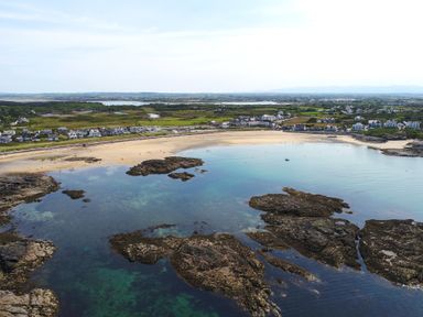 A coastal village with a sandy beach and rocky shoreline at Tyn Towyn - Ty Piws in Trearddur Bay