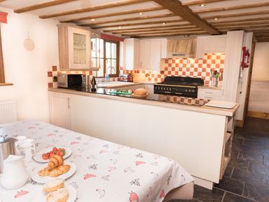 A kitchen with a black stove an island countertop and a table with plates of food at Tyddyn Morthwyl in Criccieth