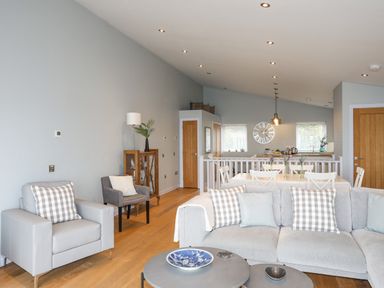 A living room with sofas and a dining area with wooden doors at Ty Glyn in Criccieth