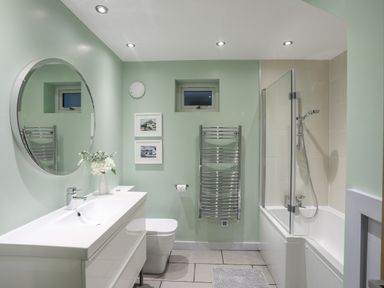 A bathroom with a sink and mirror toilet bathtub with shower and towel rack at Ty Glyn in Criccieth