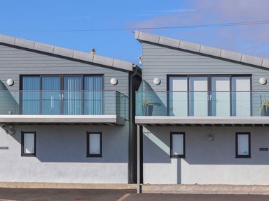 Two adjacent modern houses with glass balconies and large windows at Ty Glyn in Criccieth