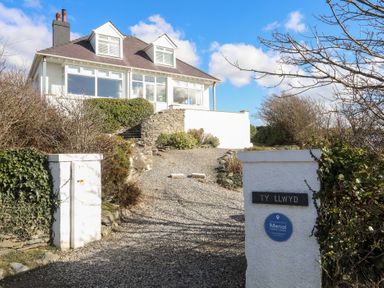 A house with a gravel driveway and white pillars at the entrance at Ty Llwyd in Trearddur Bay