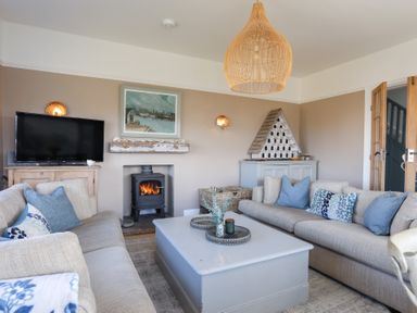 A living room with two sofas a coffee table a fireplace and a television at Ty Llwyd in Trearddur Bay