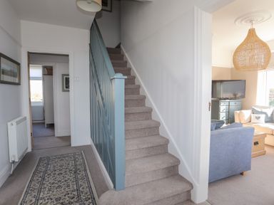 A hallway with carpeted stairs and a rug leading to other rooms at Ty Llwyd in Trearddur Bay