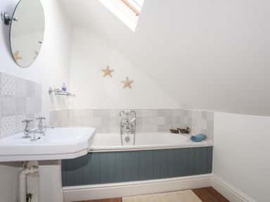 A bathroom with a bathtub and sink under a skylight at Ty Llwyd in Trearddur Bay