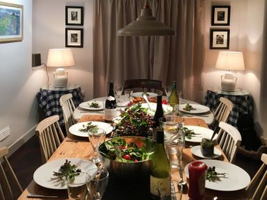 A dining room with a wooden table set with plates glasses bottles and salad bowls with chairs around at Ty Mawr Porthmadog in Porthmadog