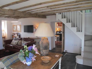 A living room with a wooden table holding a lamp and flowers a leather sofa and stairs at Ty Mawr Porthmadog