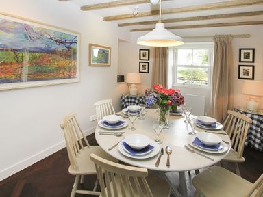 A dining room with a round table set for six people with dishes and glasses at Ty Mawr Porthmadog in Porthmadog