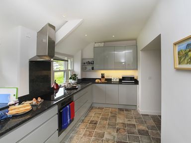 A kitchen with grey cabinets black countertops and tiled floor at Ty Mawr Porthmadog in Porthmadog