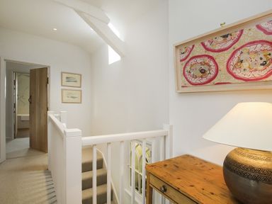 A stairway landing with a wooden table and lamp and framed artwork on the wall at Ty Mawr Porthmadog in Porthmadog