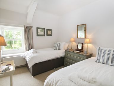 A bedroom with two single beds a dresser with lamps and a window at Ty Mawr Porthmadog in Porthmadog