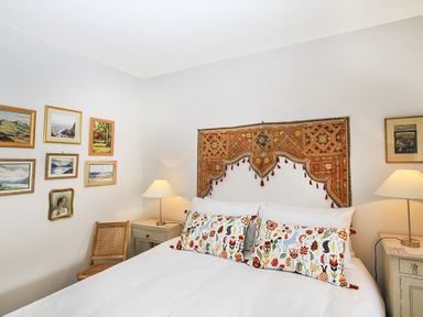 A bedroom with a bed with floral pillows and a decorative wall hanging above at Ty Mawr Porthmadog in Porthmadog