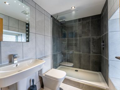 A bathroom with a sink, toilet, and a walk-in shower at Ty Nant in South Stack