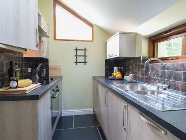 A kitchen with cabinets a sink and countertop with food items at Tyn Llwyn Cornel in Beddgelert