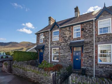 Stone terraced houses with blue doors and window frames in a rural area with hills in the background at 17 Victoria Terrace  Perthi in Nantlle