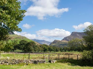 A rural landscape with green fields trees hills and a metal gate at 17 Victoria Terrace - Perthi Nantlle