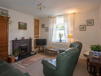 A living room with leather armchairs a fireplace a television and a coffee table at 17 Victoria Terrace - Perthi in Nantlle