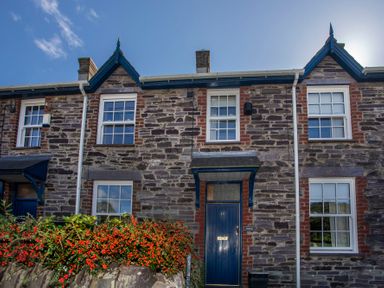 A stone terraced house with blue door and white framed windows and red berries in front at 17 Victoria Terrace Perthi in Nantlle