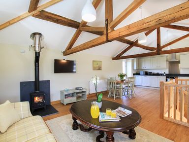 An open plan living room and kitchen with exposed wooden beams at Teal Cottage in Menai Bridge