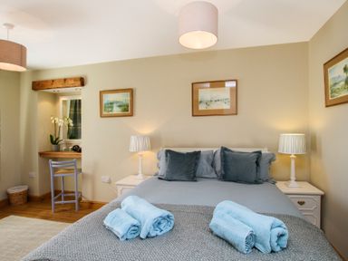 A bedroom with a bed two bedside tables lamps and towel sets at Teal Cottage in Menai Bridge