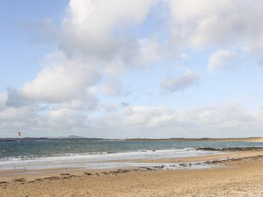A sandy beach with sea waves and a cloudy sky at Windygates in Rhosneigr